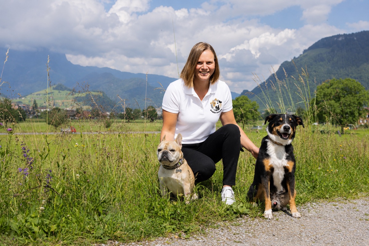 Patricia Streun vom Doggy Deluxe Team mit zwei Hunden auf einer Bergwiese